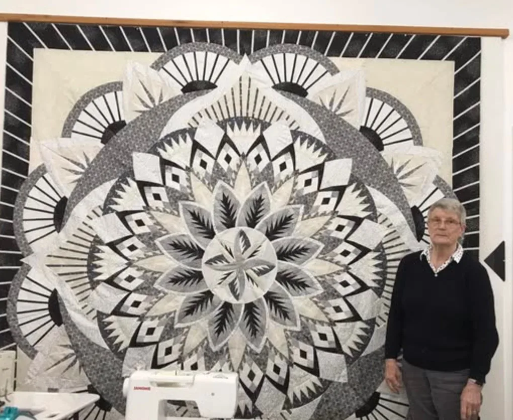 Guest beside a finished quilt on the design wall