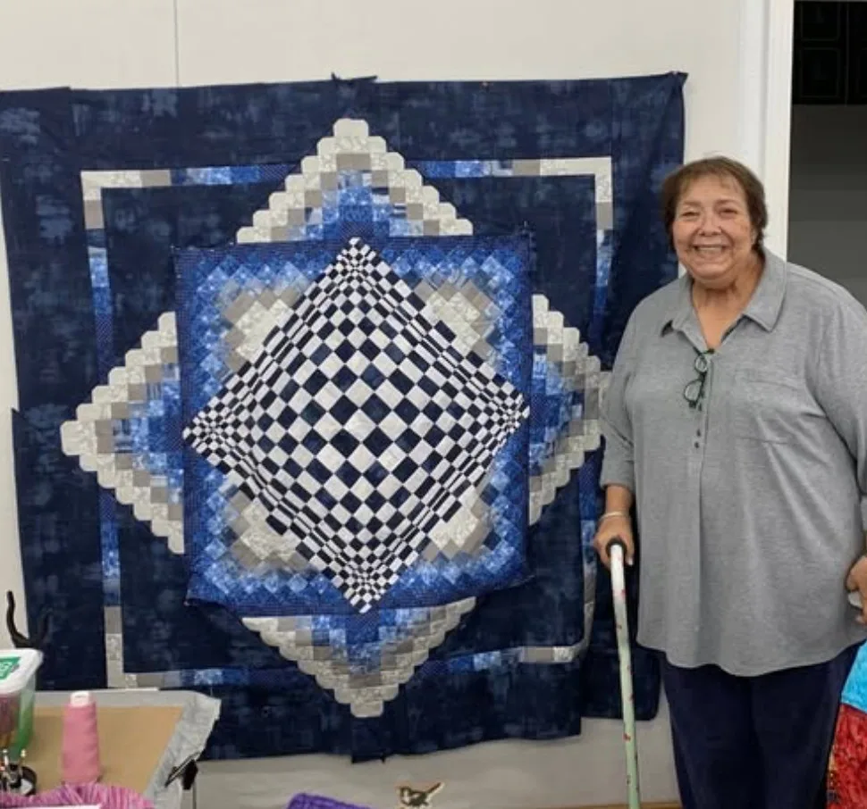 Quilter with a finished quilt on the design wall