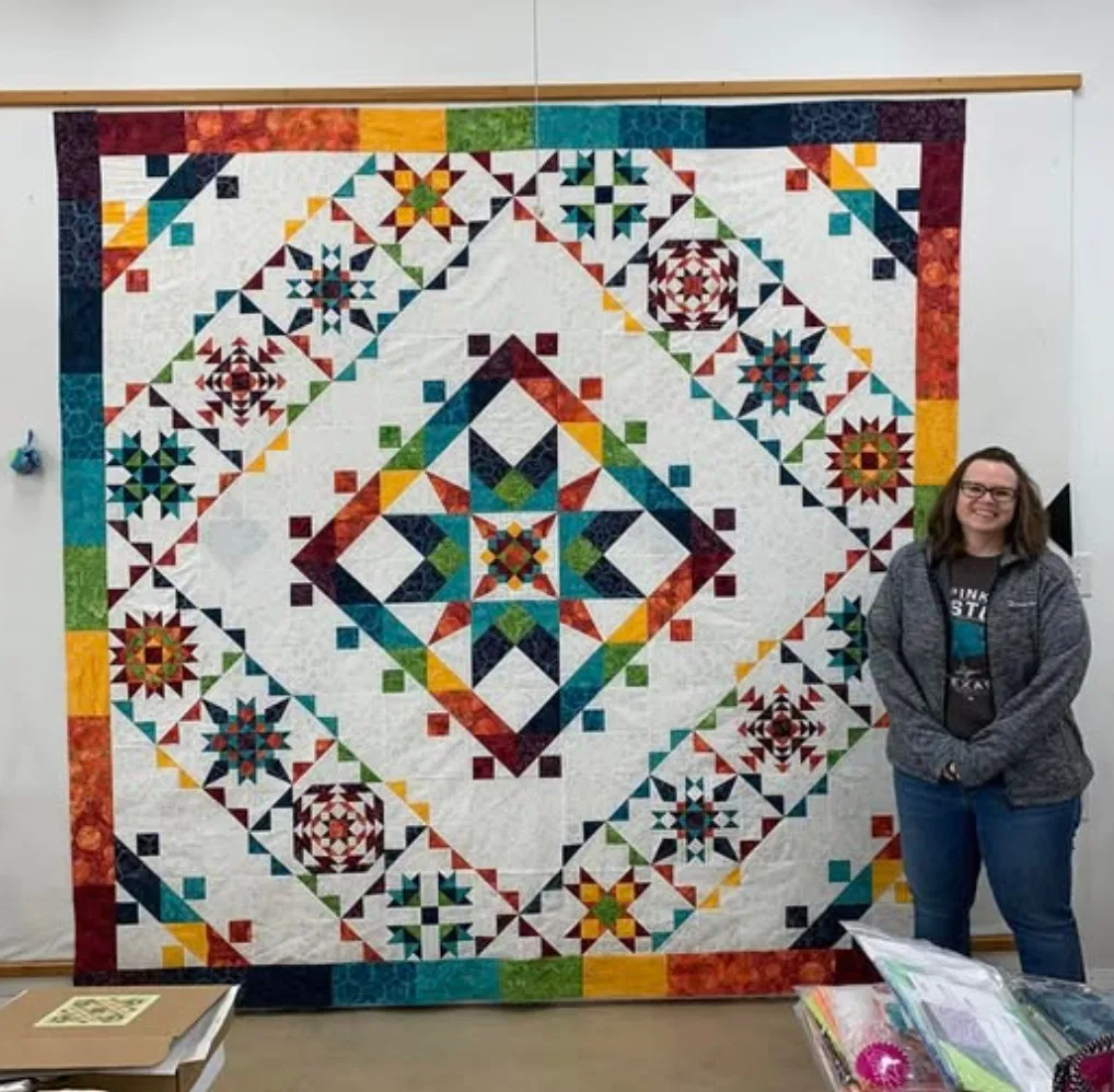 Guest with a finished quilt on the design wall