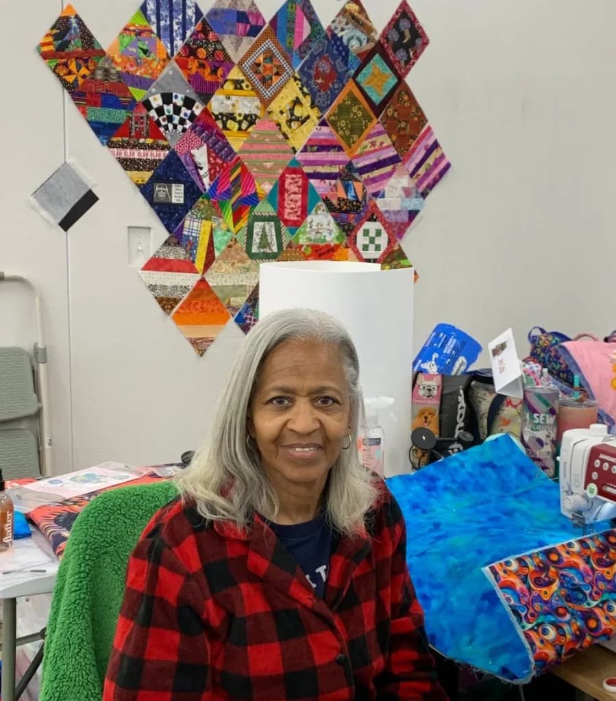Quilter at her station with a colorful design wall