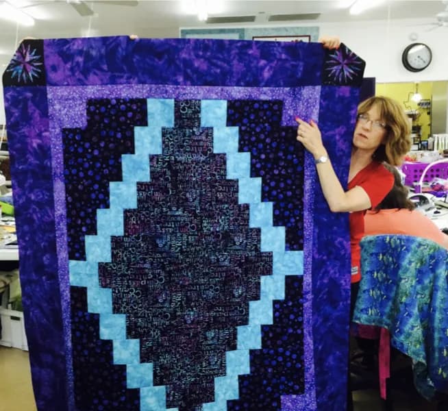 Guest holding a Mariner's Compass quilt in the workroom