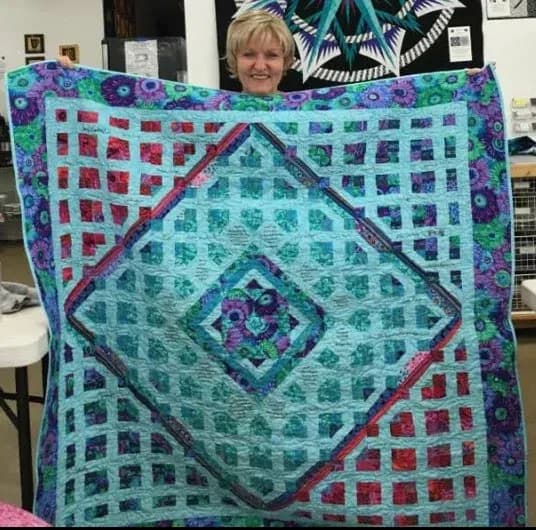 Guest with a finished quilt at show and tell