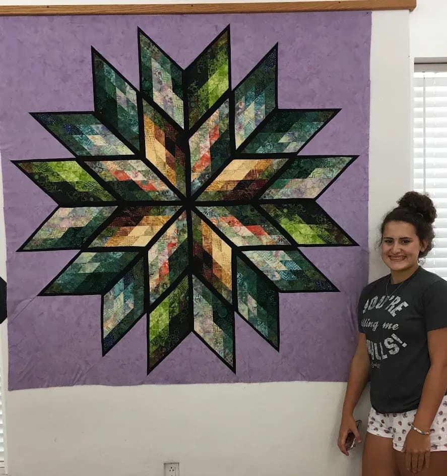 Young guest beside a finished quilt on the design wall