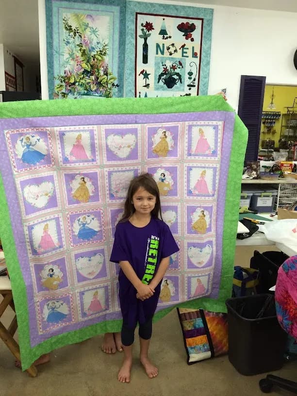 Young maker holding a finished quilt at the Buddy Retreat
