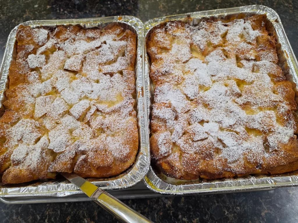 Two pans of overnight French toast dusted with powdered sugar