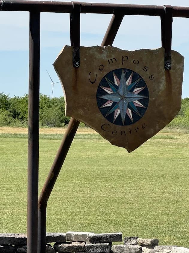 Compass Centre stone sign with compass rose against open Texas sky