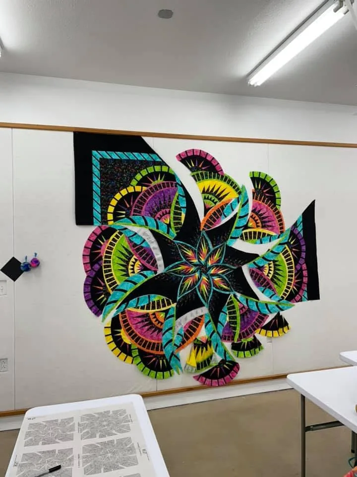 Colorful radial quilt in progress pinned on the design wall