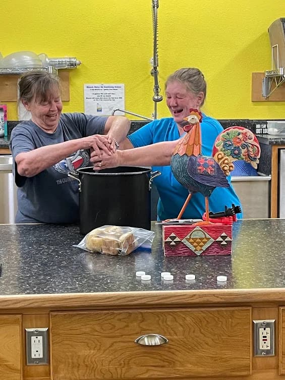 Two guests laughing while stirring a pot in the Centre kitchen