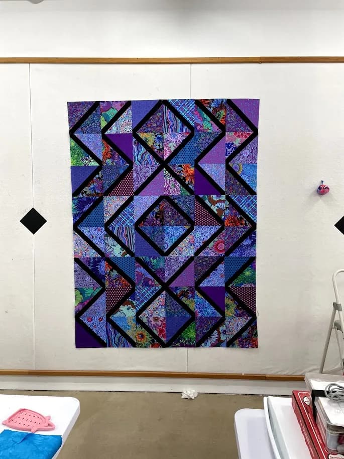 Purple and teal geometric quilt top finished on the design wall