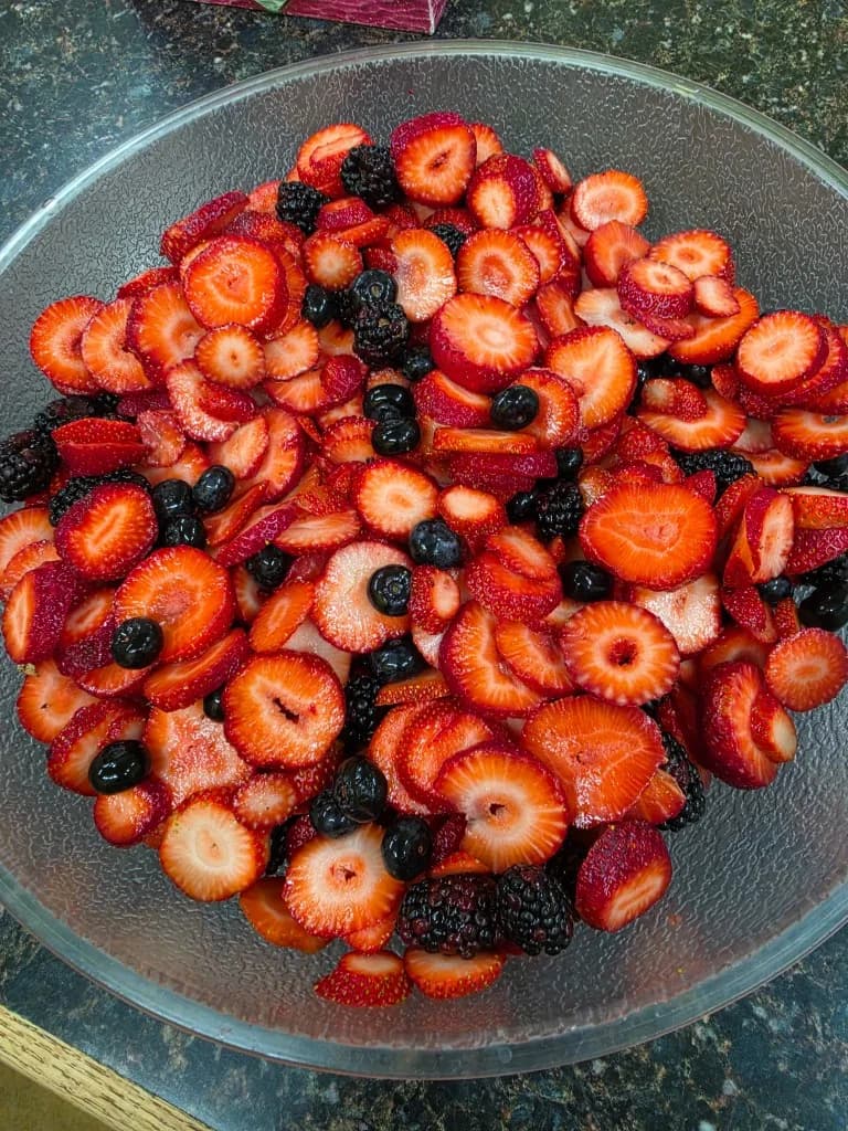 Glass bowl of sliced strawberries, blackberries, and blueberries