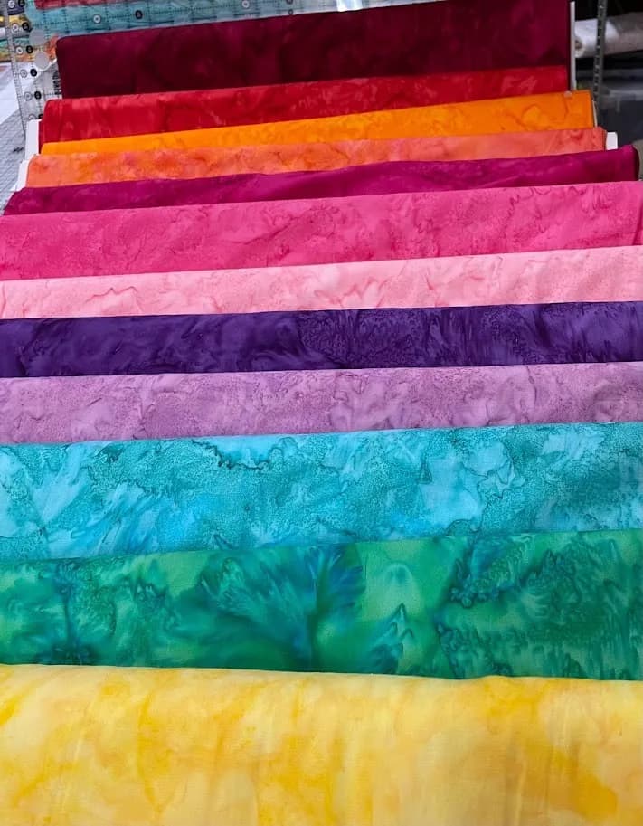 Stacked batik fabrics in red, pink, purple, teal, green, and yellow